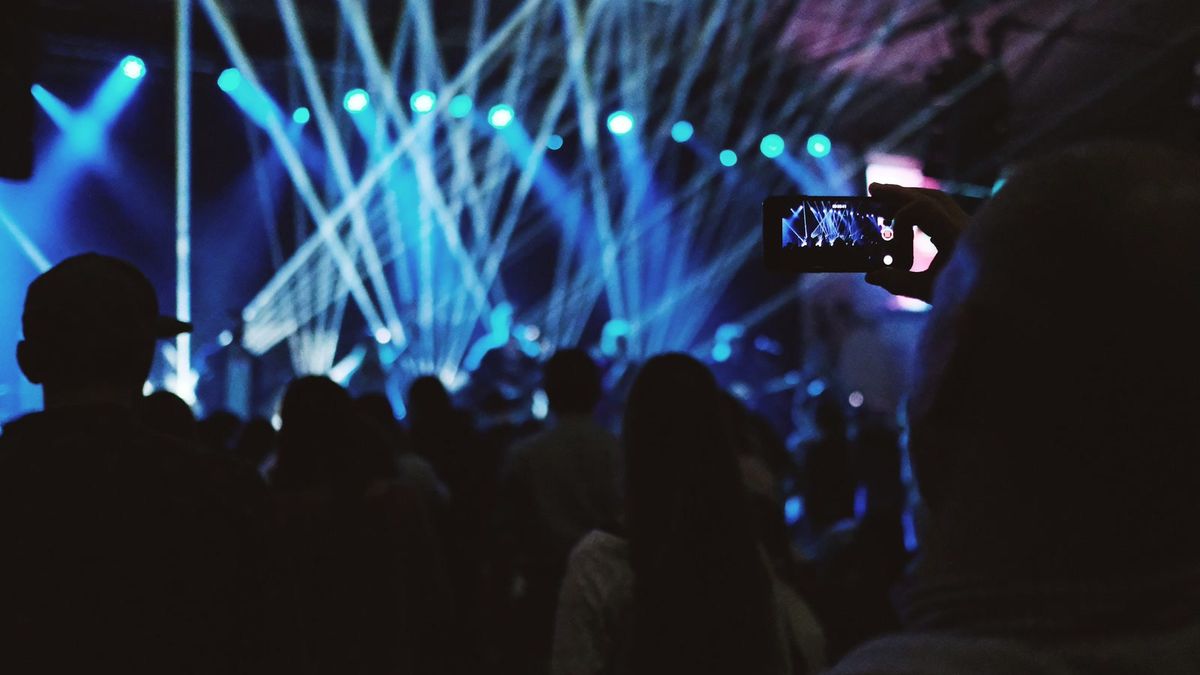Handen filmen een festivalpodium met een smartphone — short-form content van Spits Media